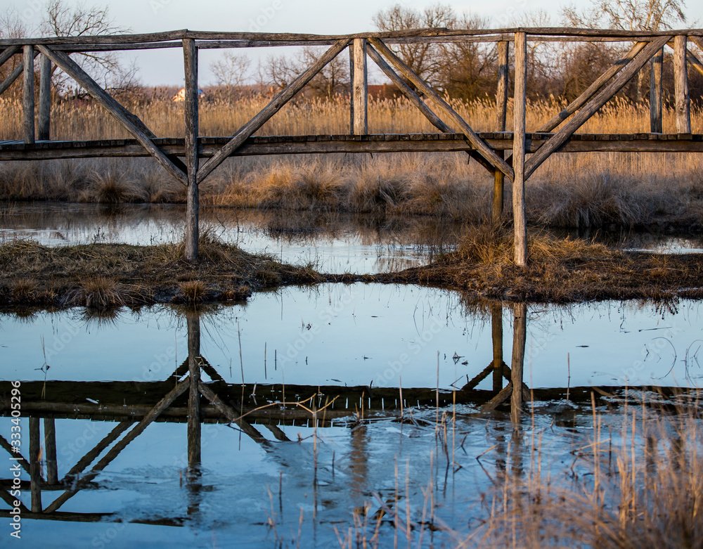 An old wood bridge and it's reflection.