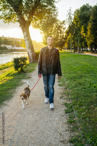 Young man takes his beloved dog for a walk in the park at sunset - Millennial in a moment of relaxation with his four-legged friend
