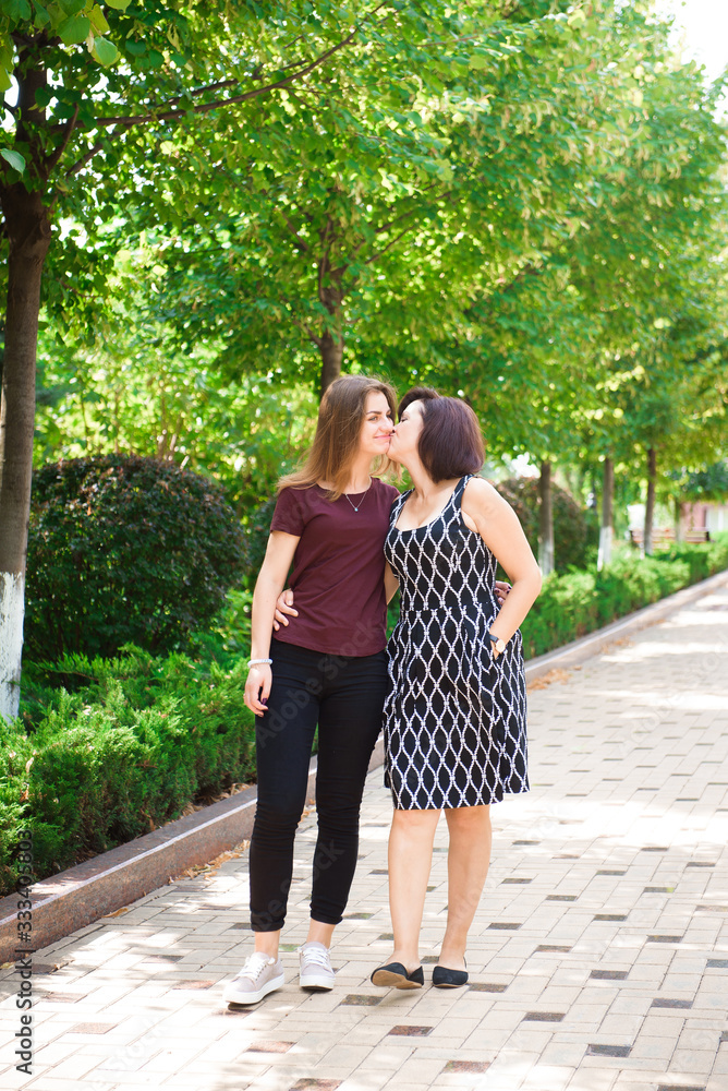 Mature mother hugging with her teen daughter outdoor in nature on sunny day. Mature mother hugging with her teen daughter outdoor in nature on sunny day.