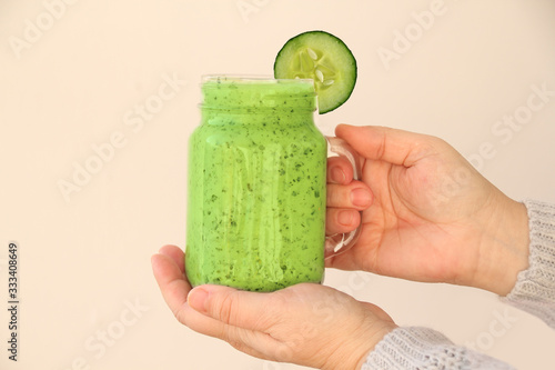 girl holds mason jar mug filled with healthy smoothie made from green vegetables of cucumbers, paprika, spinach, concept of healthy eating, veganism