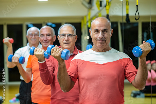 Gruppo di anziani che si allena in palestra con i pesi