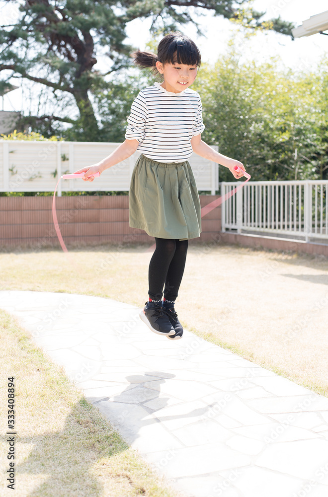 庭で縄跳びの練習をする小学生の女の子 Stock Photo Adobe Stock