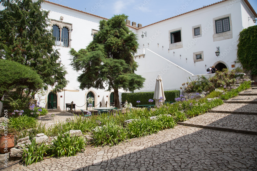Obraz premium Dorf Óbidos, Portugal: Garten Innenhof mit Naturstein Treppen umrahmt von Reihen mit lila und weissen Schmucklilien