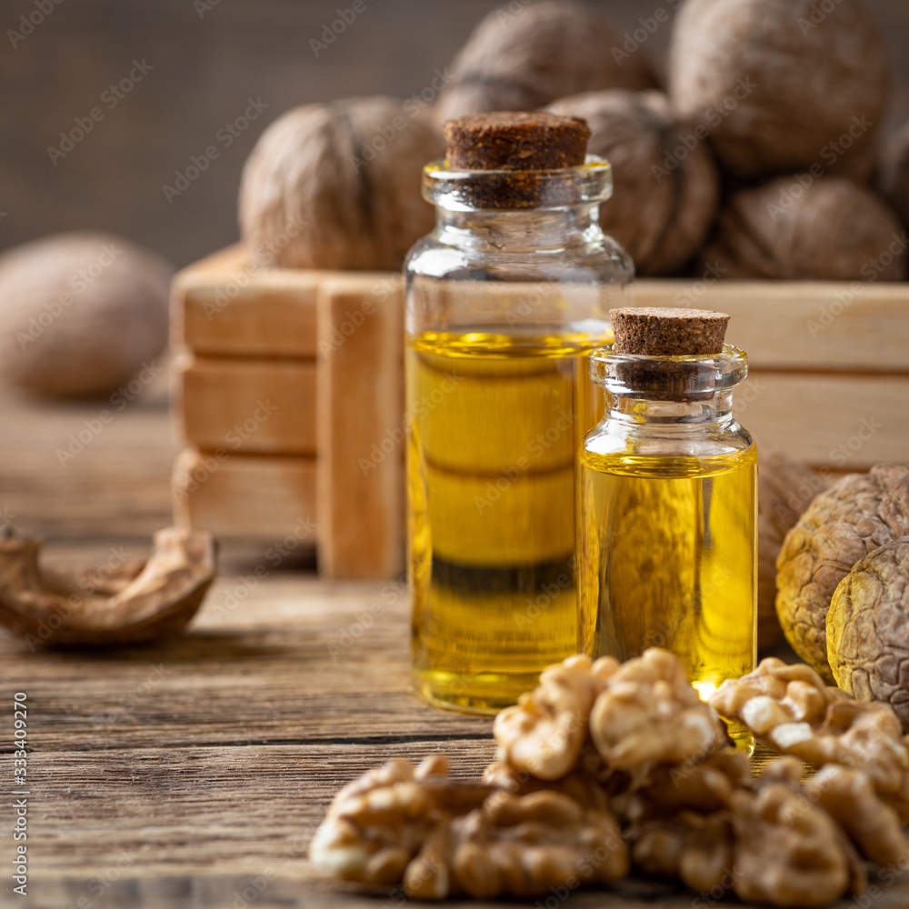 Glass bottle with walnut oil and walnut kernel on a wooden table. Cosmetic and therapeutic product. Glass bottle with walnut oil and walnut kernel on a wooden table. Cosmetic and therapeutic product.