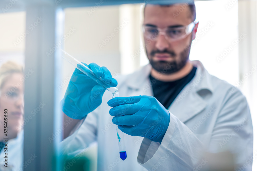 Young handsome scientist in laboratory working with test tubes and doing research Young handsome scientist in laboratory working with test tubes and doing research