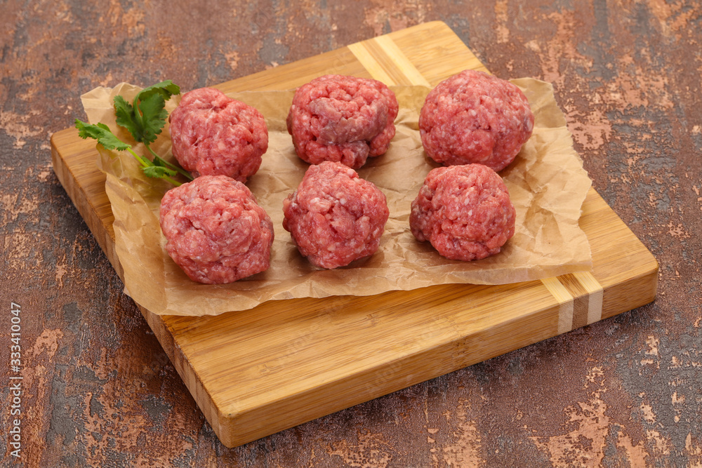 Raw meatball over wooden background Raw meatball over wooden background