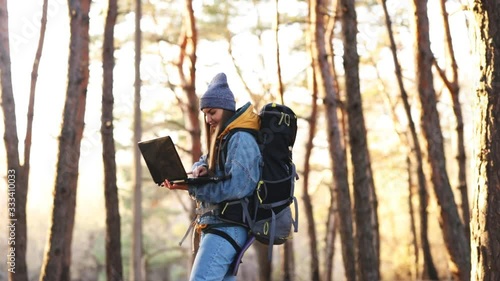 Wallpaper Mural Young attractive girl with a large hiking backpack communicates online with friends using a laptop in the forest. Remote work on a journey. Online education. Insulation. Freelance. Correspondence. Torontodigital.ca