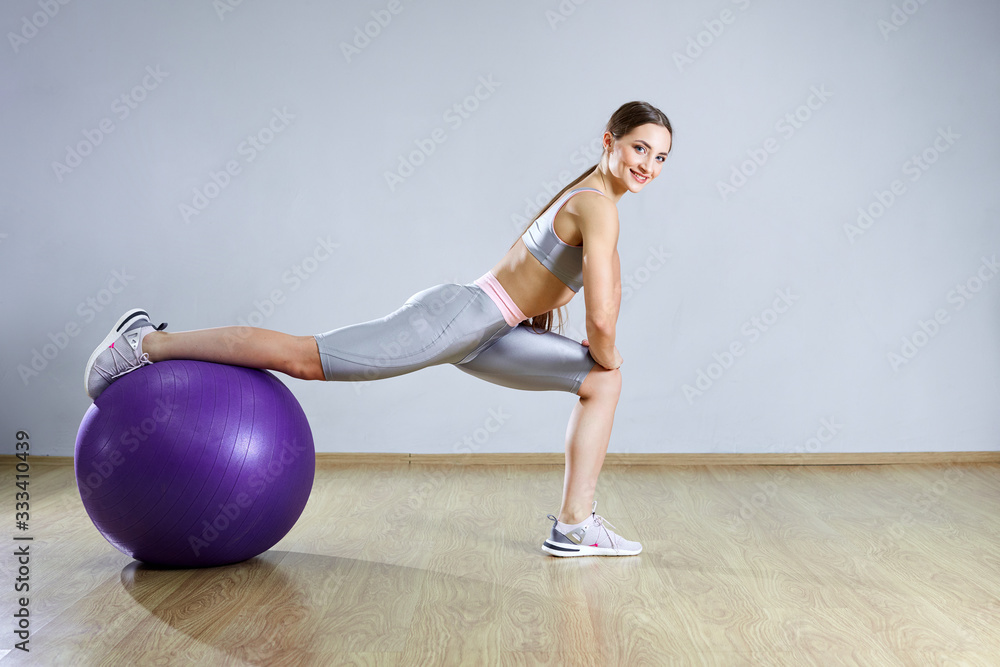 Young fit woman exercising in a gym. Sports girl is training cross fitness with Pilates Balls. Young fit woman exercising in a gym. Sports girl is training cross fitness with Pilates Balls.