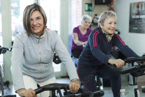 gruppo di donne anziane fa spinning in una palestra photo