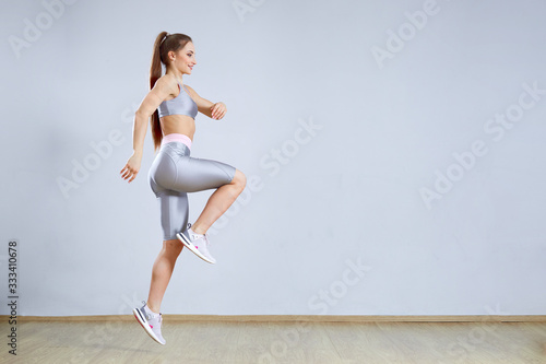 Fit woman doing cardio interval training in gym. Woman in sportswear is posing and jumping. Fitness and sport concept.