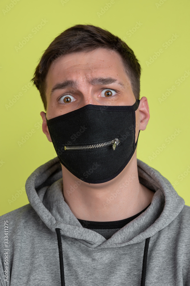 Scared eyes. Caucasian man's portrait isolated on yellow studio background. Freaky male model in black face mask. Concept of human emotions, facial expression, sales, ad. Unusual appearance. Scared eyes. Caucasian man's portrait isolated on yellow studio background. Freaky male model in black face mask. Concept of human emotions, facial expression, sales, ad. Unusual appearance.