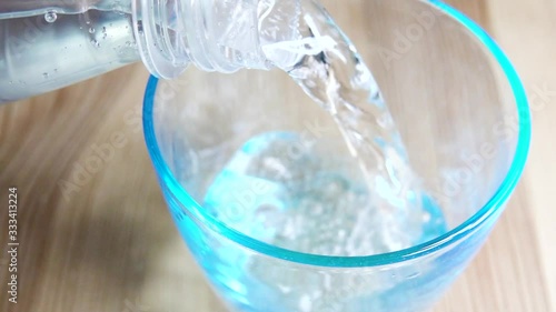 Slow motion close up of pouring fresh water in glass on table. Clean refreshing drink. Natural refeshment. photo