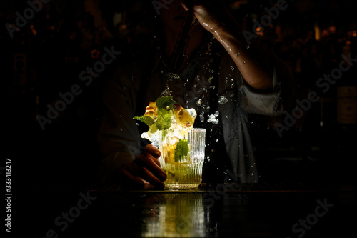 woman at dark bar energetically crushed cocktail with slices of citrus and ice Fotobehang