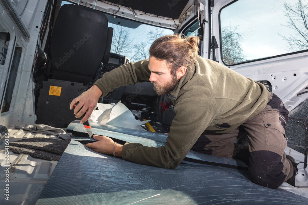 Man inside his camper van cutting insulation material 