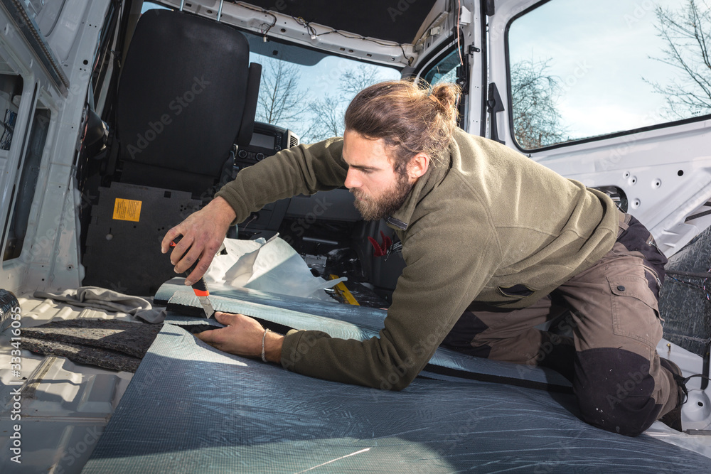 Man inside his camper van cutting insulation material Man inside his camper van cutting insulation material