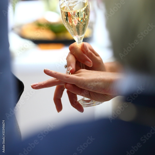 hands holding a glass of white wine with on one finger a wedding ring © bestjeroen