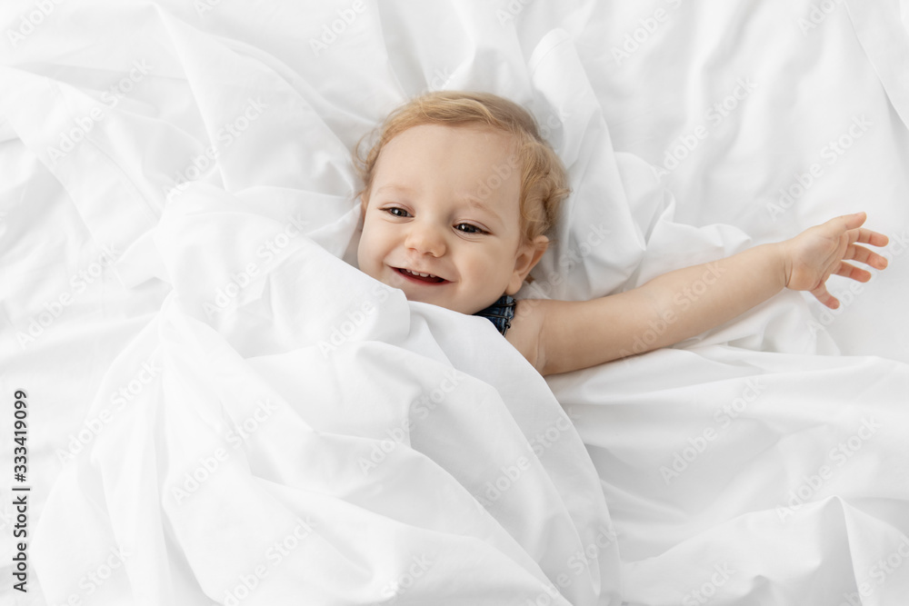 Happy baby lying in white sheets Happy baby lying in white sheets