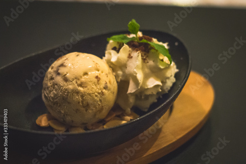 a ball of coconut ice cream and almond flakes and whipped cream and mint leaves