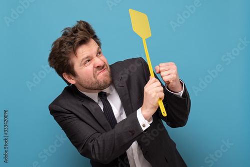 man in suit holding a fly swatter wanting to kill annoying mosquito photo