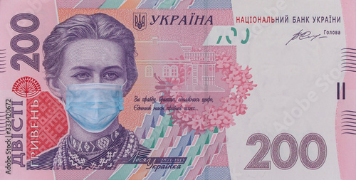 COVID-19 coronavirus in Ukraine. 200 hryvnia banknote with Lesya Ukrainka in a medical mask. Global financial and economic crisis has affected Ukraine. Ukrainian money, coronavirus concept, montage photo