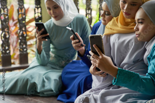 women with traditional clothing using smart phone during ramadan festival celebration