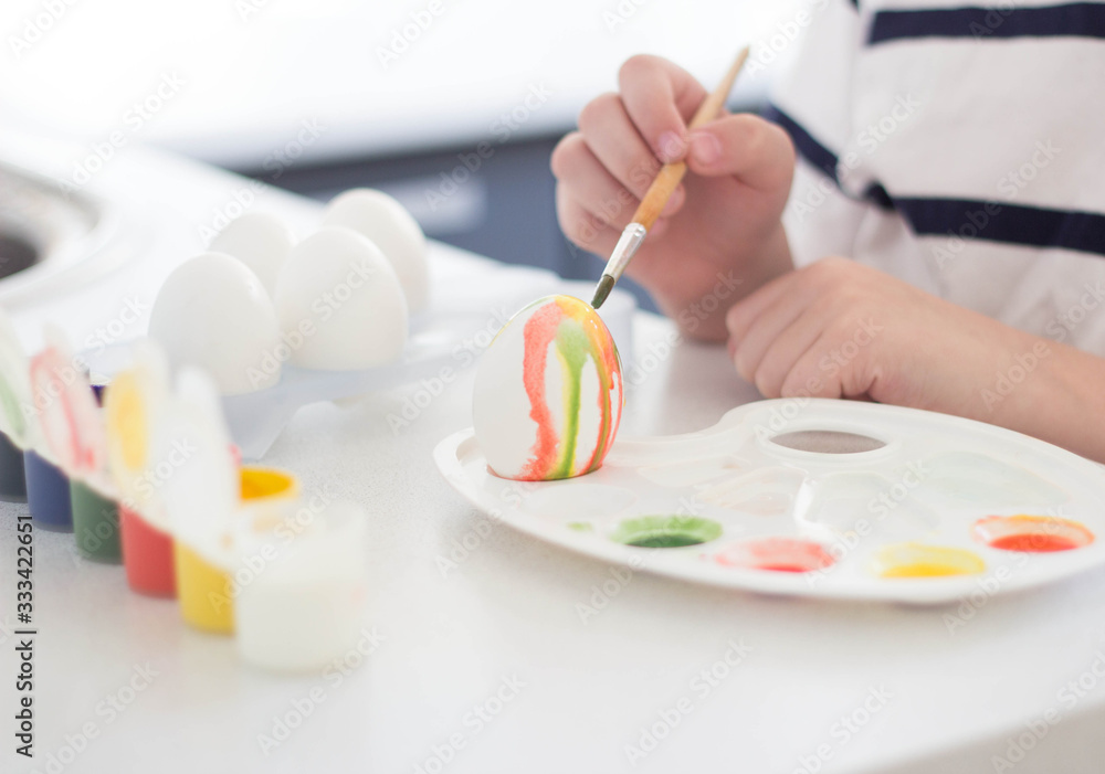 a child paints eggs with watercolors and gouache waits for Easter and plays a child paints eggs with watercolors and gouache waits for Easter and plays