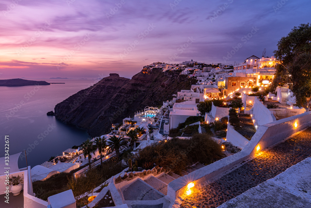 Amazing sunset landscape in Santorini, Greece. Romantic sky colors with lights in the village. Stairs and houses, hotels resorts for tourism. Famous Europe travel vacation destination. Sunset landscap