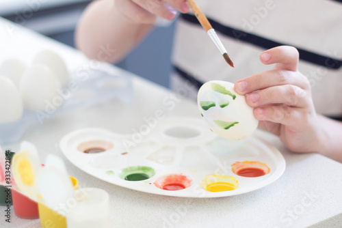 a child paints eggs with watercolors and gouache waits for Easter and plays