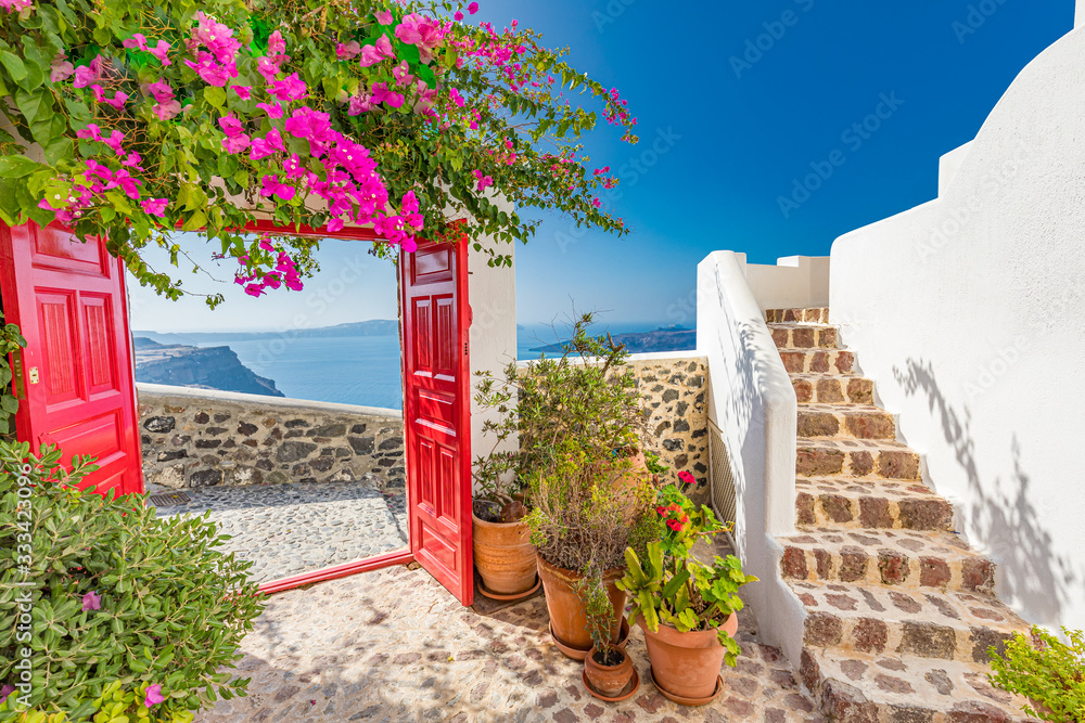 Obraz premium Fantastyczny krajobraz wakacji letnich. Biała architektura Santorini z czerwoną bramą i różowymi kwiatami. Spokojne tło podróży, sceneria luksusowej turystyki, kamienne schody pod błękitnym niebem.