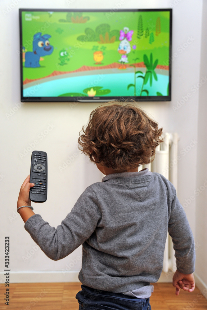 Children boy 5 years old watching tv television with controller in hand