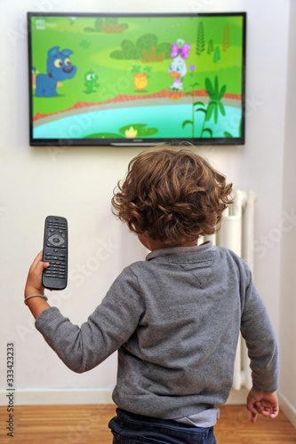 Obraz na płótnie Children boy 5 years old watching tv television with controller in hand w salonie