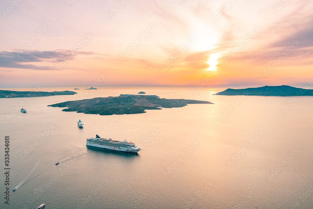 Amazing seascape view of caldera in Santorini, Greece with cruise ships at sunset. Cloudy dramatic sky with beautiful sunset light. Cruise ships in Santorini bay