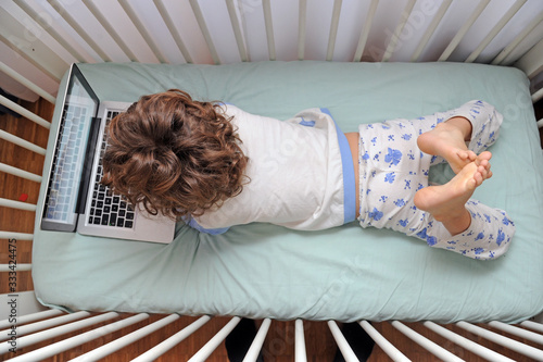 Cuadro en lienzo Young child 4 years old in the bed looks lap top computer during n-cov19 coronav