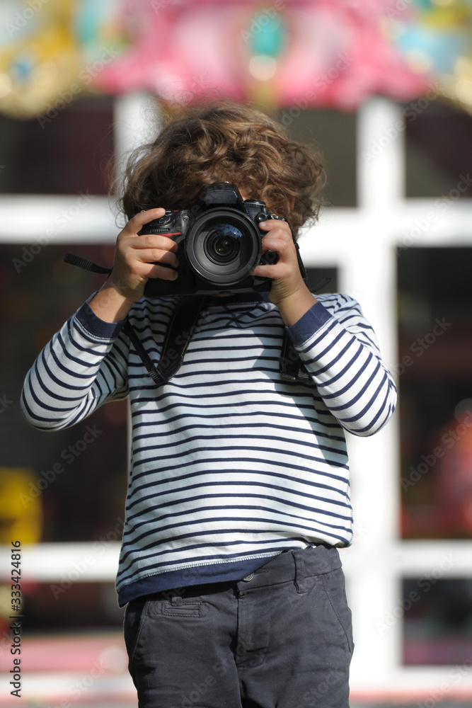 Child learns to take pictures in a park with a professional reflex camera