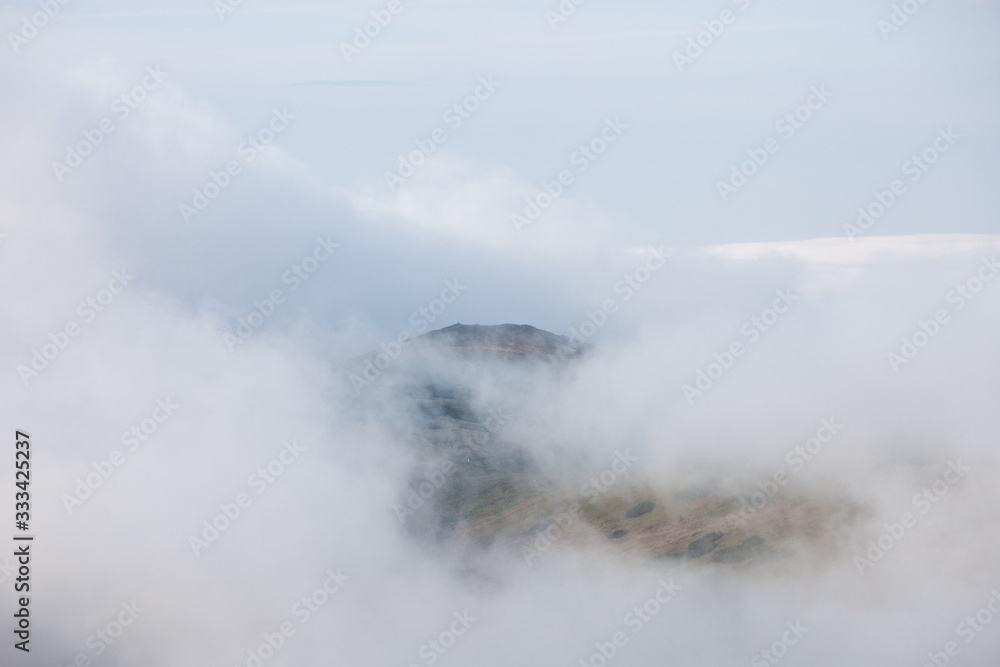 Mountain range through clouds and fog at stormy summer day