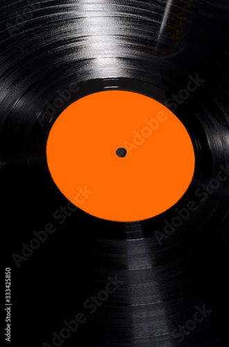 Vertical image.Closeup of texture of vinyl record with blank bright orange lable.Empty space