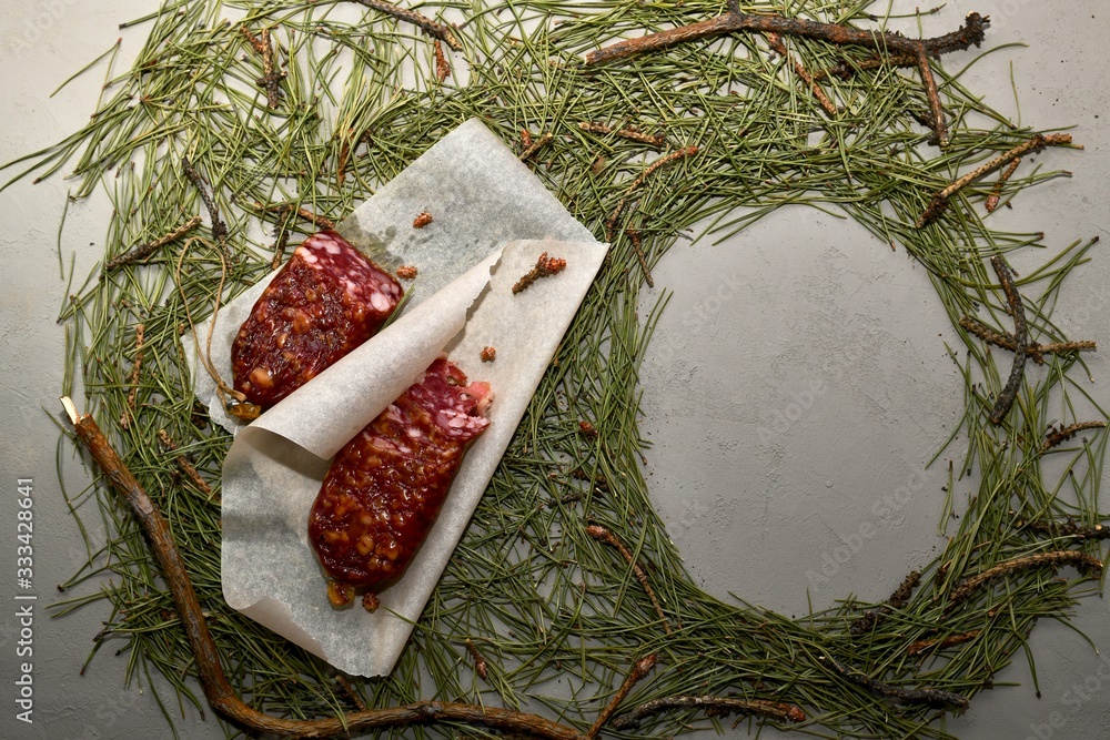 Dried sausage from beaver meat on parchment paper and an empty frame ...