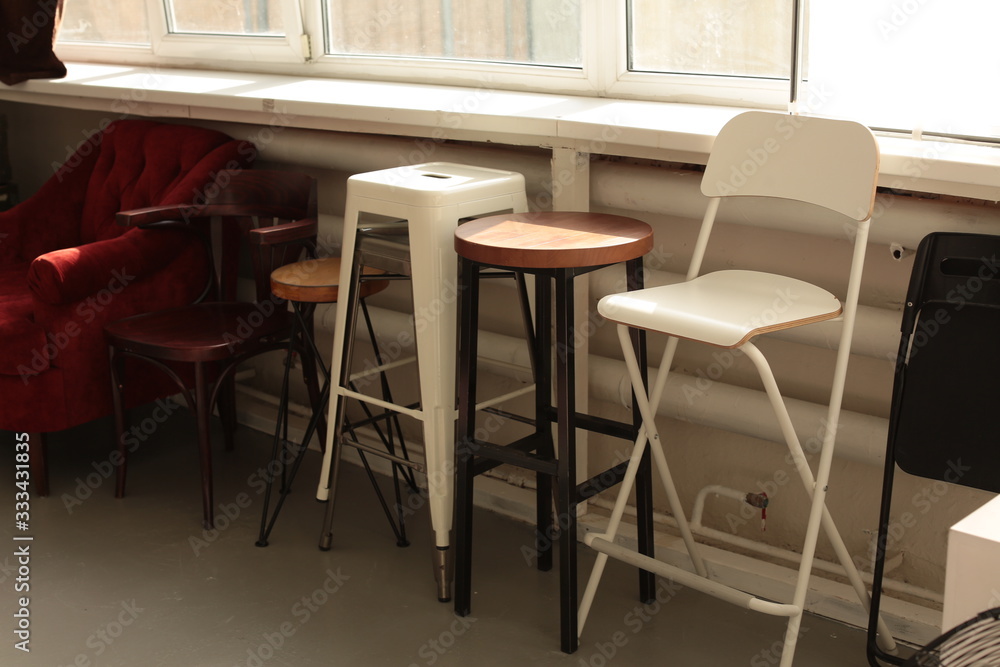 Fototapeta premium various different chairs stools stand along the wall by the window