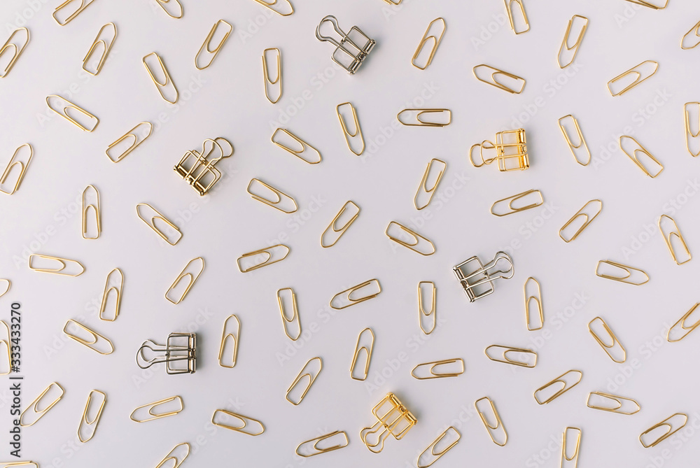 Set of silver and gold paper clips on light grey background. Flat lay. Office and business concept. Set of silver and gold paper clips on light grey background. Flat lay. Office and business concept.