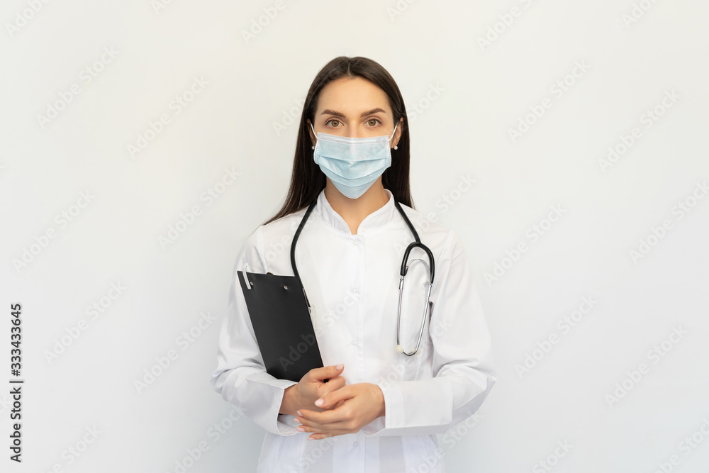 Friendly female doctor in a protective medical mask with a stethoscope, holds a folder in his hands, Friendly female doctor in a protective medical mask with a stethoscope, holds a folder in his hands,