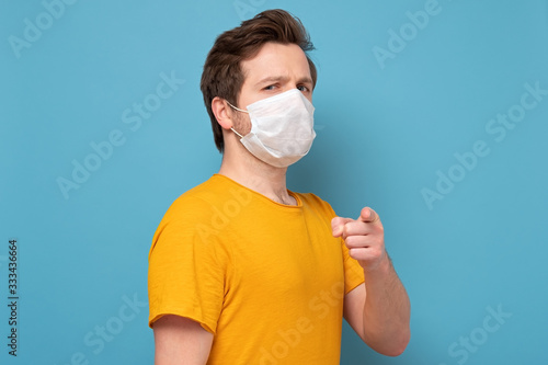 man pointing you with index finger with single use medical mask to prevent infection photo