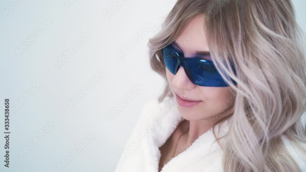 Close up: pretty fair haired lady in protective sunglasses undergoes laser hair removal procedure in modern cosmetic salon Close up: pretty fair haired lady in protective sunglasses undergoes laser hair removal procedure in modern cosmetic salon