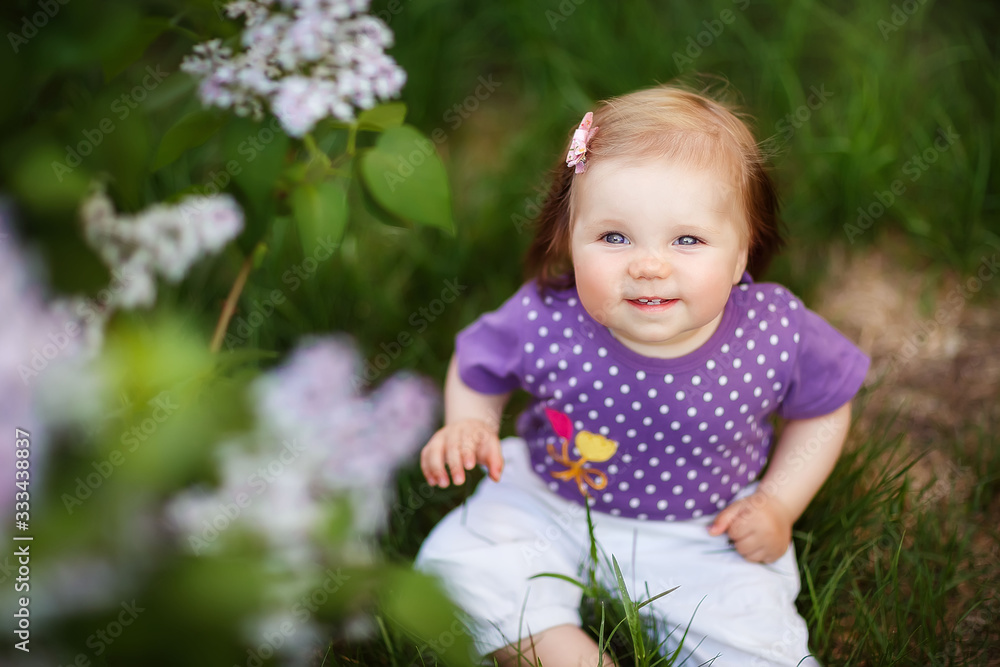 little girl crawling sitting in the grass at the lilac Bush, spring has come, cute baby, may, flowering little girl crawling sitting in the grass at the lilac Bush, spring has come, cute baby, may, flowering