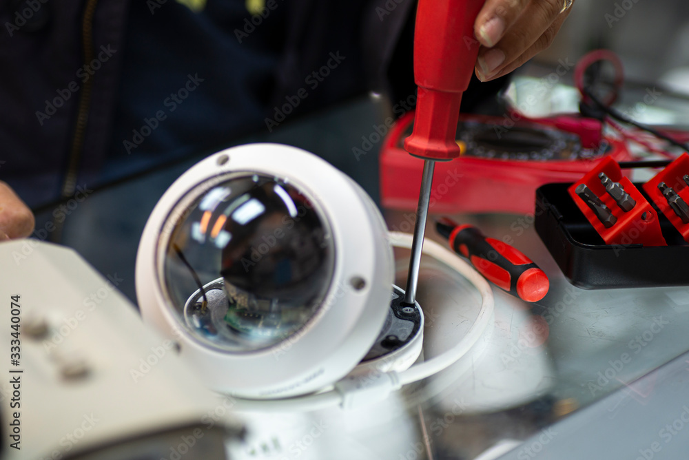 technician repairs CCTV camera on the glass cabinet .