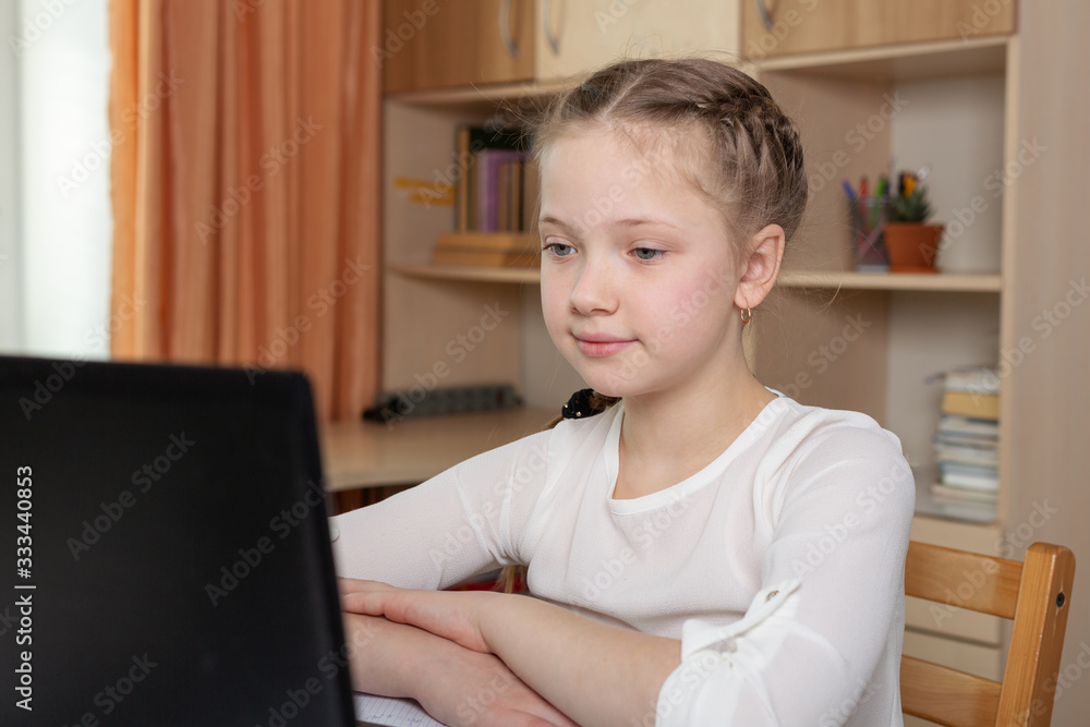 Schoolgirl looks at a laptop screen. Distance learning online education, home school, home education, quarantine concept Schoolgirl looks at a laptop screen. Distance learning online education, home school, home education, quarantine concept