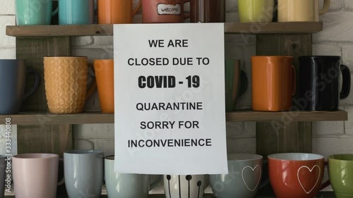 Zoom in shot of biohazard concept of living in a new reality of coronavirus epidemic hysteria cafe owner sticks advertisement on quarantine measures to contain virus pinned on shelf with colorful mugs