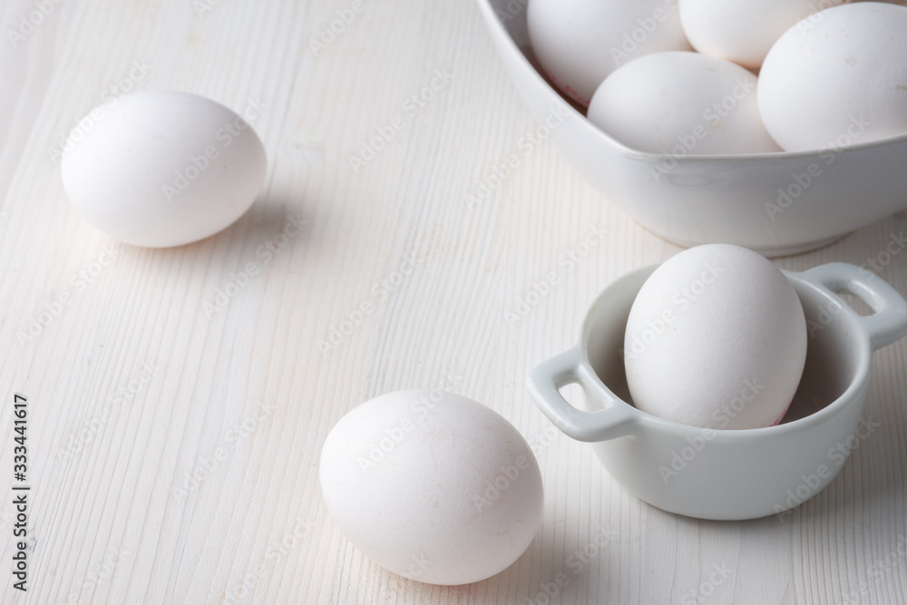 Top view of white eggs in a white bowls, with selective focus, on white wooden table horizontally, with copy space Top view of white eggs in a white bowls, with selective focus, on white wooden table horizontally, with copy space