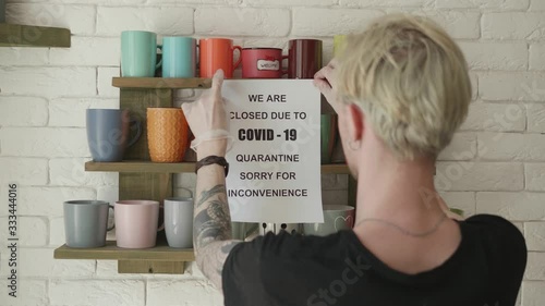 Biohazard concept of living in a new reality of coronavirus epidemic hysteria cafe owner sticks advertisement on quarantine measures to contain virus pinned on shelf with colorful mugs