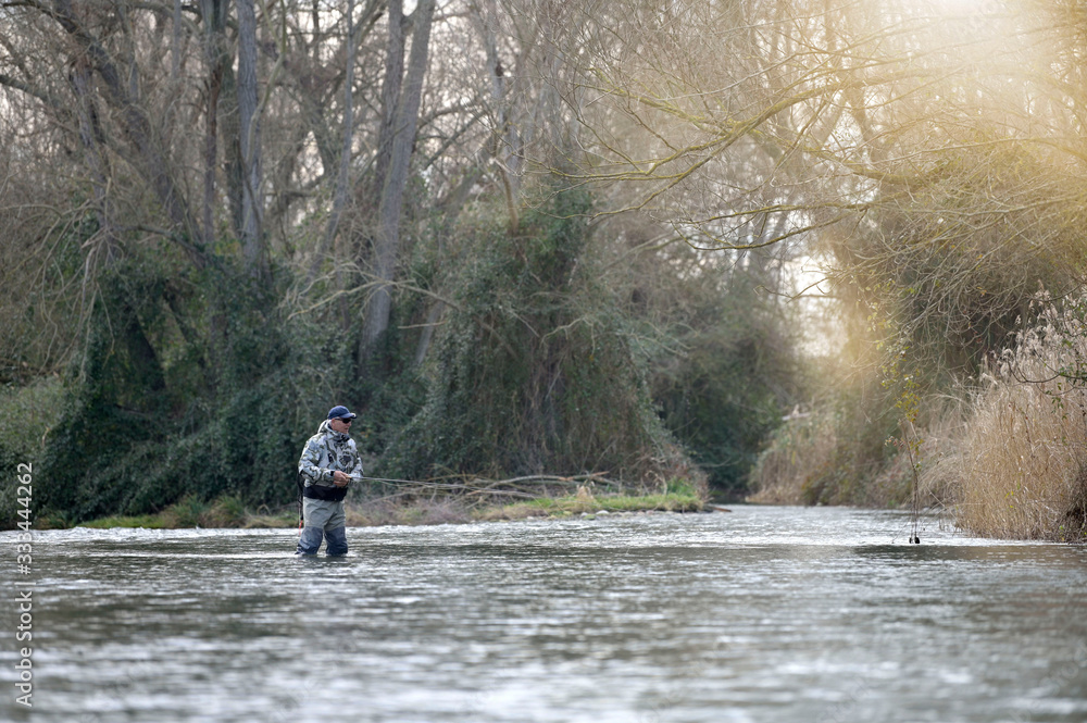 fly fisherman in river in winter