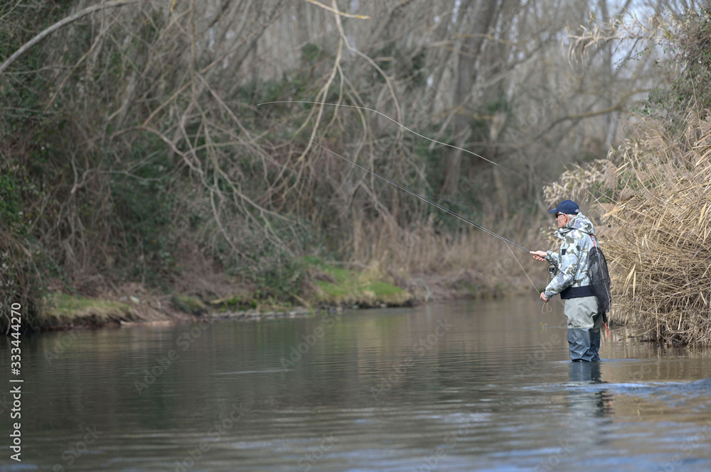 fly fisherman in river in winter